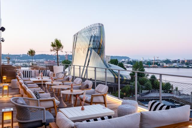 Terrasse avec vue panoramique, lumières tamisées et canapés ultra confortables à l’hôtel Renaissance de Bordeaux. Une réalisation menée par l’agence d'architecture intérieure Maison Malapert.