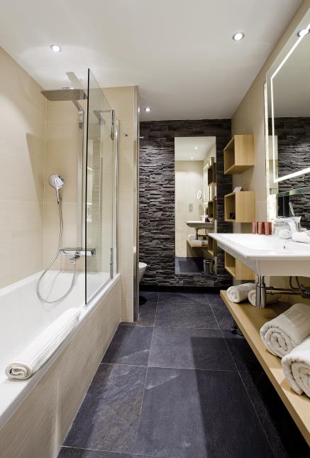 Alliant granit et tons clairs, les salles de bains se veulent contemporaines.