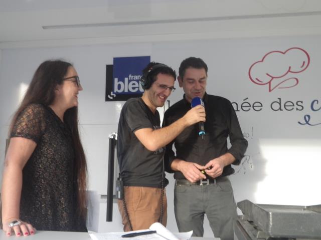 Hugo Desnoyer au micro d Alexandre Zazerra, animateur France Bleu Mayenne) aprés la signature en qualité de parrain du camion de ' La Tournée des cordons bleus', avec Anne-Marie Amoros (à gche).
