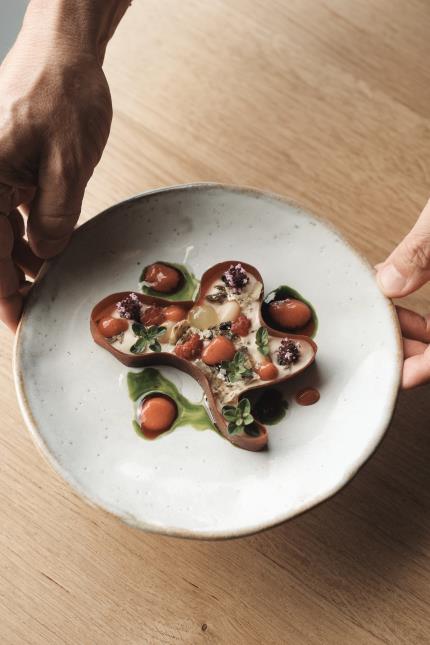 Un plat de Nicolas Conraux, les "Tomates 2024, basilic", composé de tomates fermentées, basilic, coco de Paimpol, piment et baies du jardin préservés au verjus